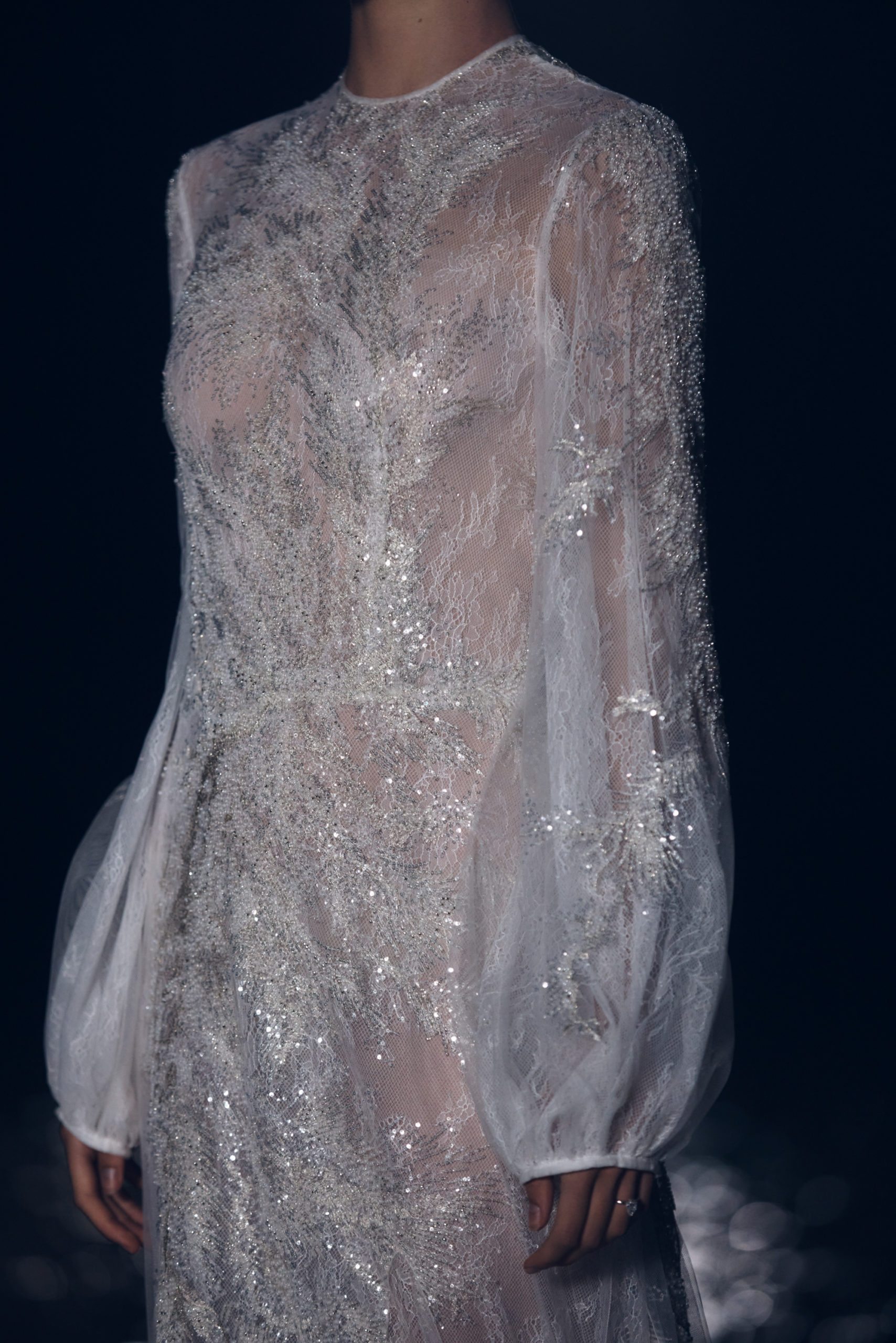 Costarellos bridal gown, featring lace and embroidered beaded detailing on sheer fabrications with rounded sleeves.