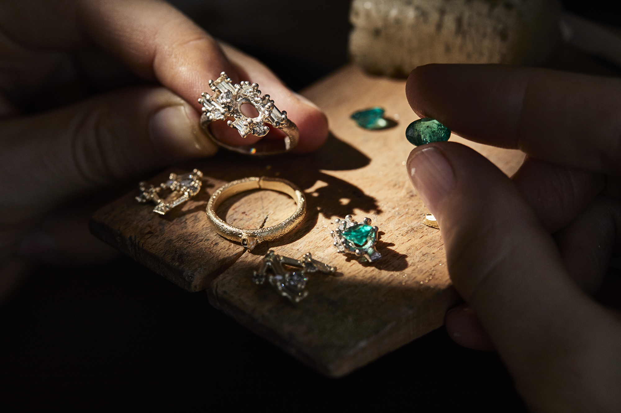 Ruth Tomlinson ring being set surrounded by ethically sourced, loose emerald stones